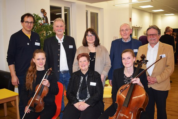 Man sieht eine Gruppe Personen mit zwei Musikerinnen. 