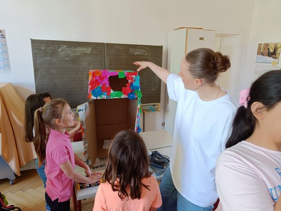 Das Bild zeigt Kinder die unter Anleitung basteln.  