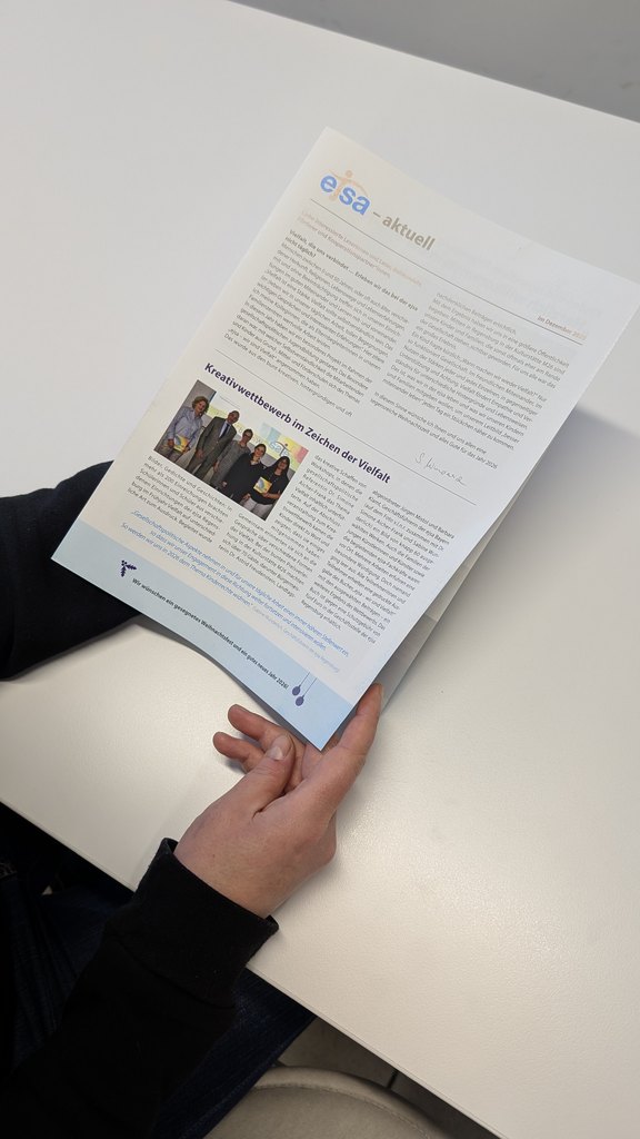 Quelle: ejsa Regensburg / Valentum Kommunikation (Chayenne Wache) Das Bild zeigt eine Printpublikation in Händen gehalten.