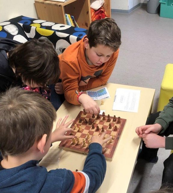 Das Bild zeigt mehrere Kinder beim Schachspiel am Tisch.