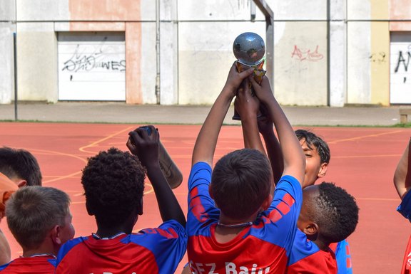 Kinder strecken einen Pokal in die Höhe.  
