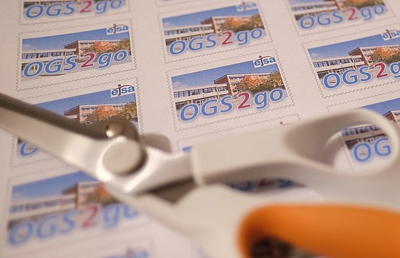Das Bild zeigt eine Schere auf Briefmarken liegen.