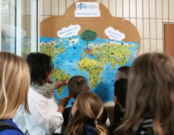 Das Bild zeigt Schüler vor einer Weltkarte.