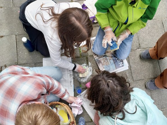 Das Bild zeigt junge Menschen bei der Reinigung von Stoplersteinen