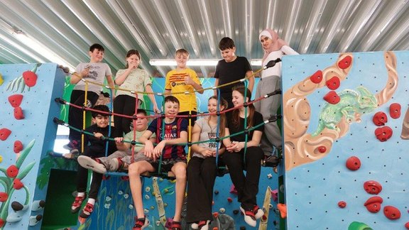 Man sieht eine Gruppe Kinder in einer Boulder-Halle.