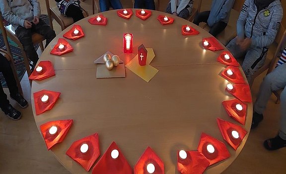 Das Bild zeigt einen Tisch, geschmückt mit brennenden Kerzen.
