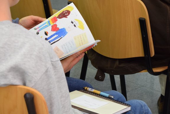 Das Bild zeigt die seitliche Ansicht von den Händen einer Person, die in einem Buch blättert.