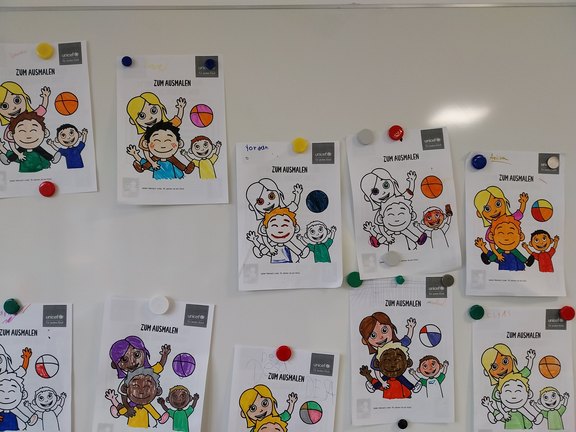 Man sieht mehrere ausgemalte Bilder, die an der Wand aufgehängt sind.  