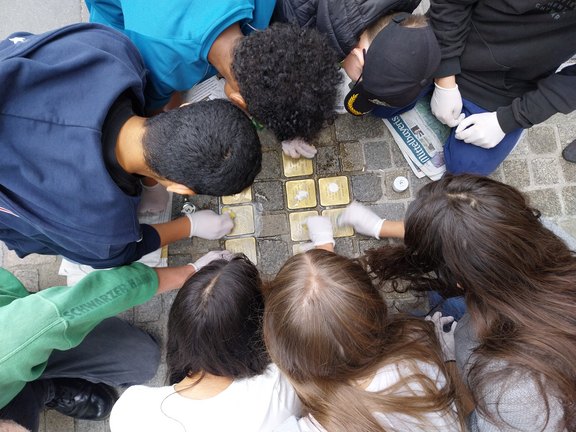 Draufsicht auf Kinder, die Stolpersteine putzen.  