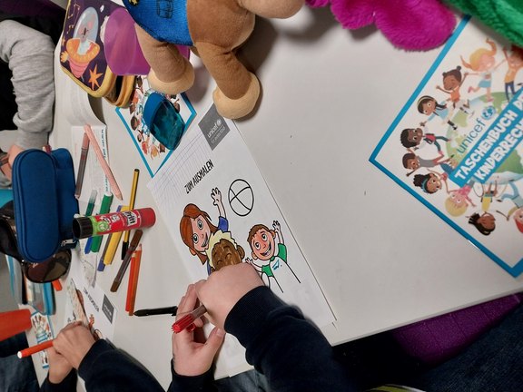Dr. Simone Aicher-Frank Man sieht Kinderhände, die ein Bild ausmalen.