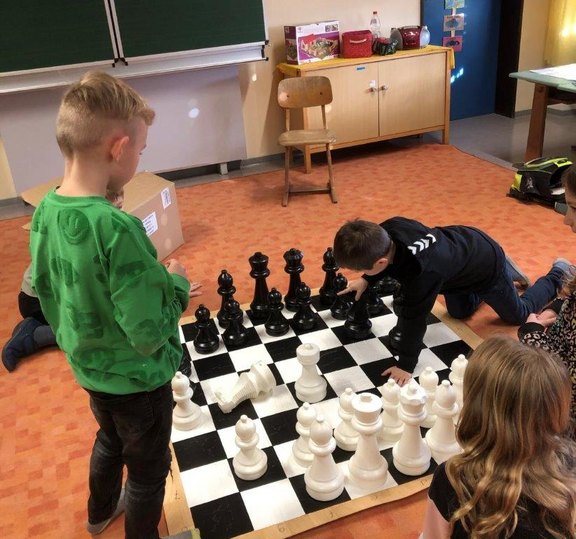Das Bild zeigt mehrere Kinder bei einem Riesen-Schachspiel.