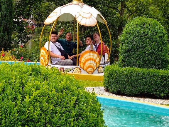 Da sBild zeigt vier Menschen in einem Fahrgeschäft in einem Freizeitpark.