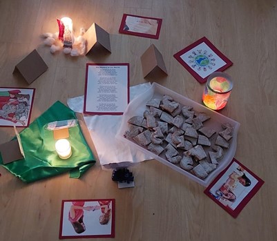 Das Bild zeigt Kärtchen, Kerzen und Kekse in einer Box.