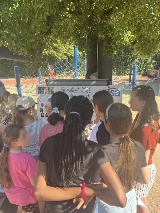 ejsa Regensburg Das Bild zeigt viele Kinder, welche um ein Whiteboard mit vielen gemalten Gesichtern stehen.